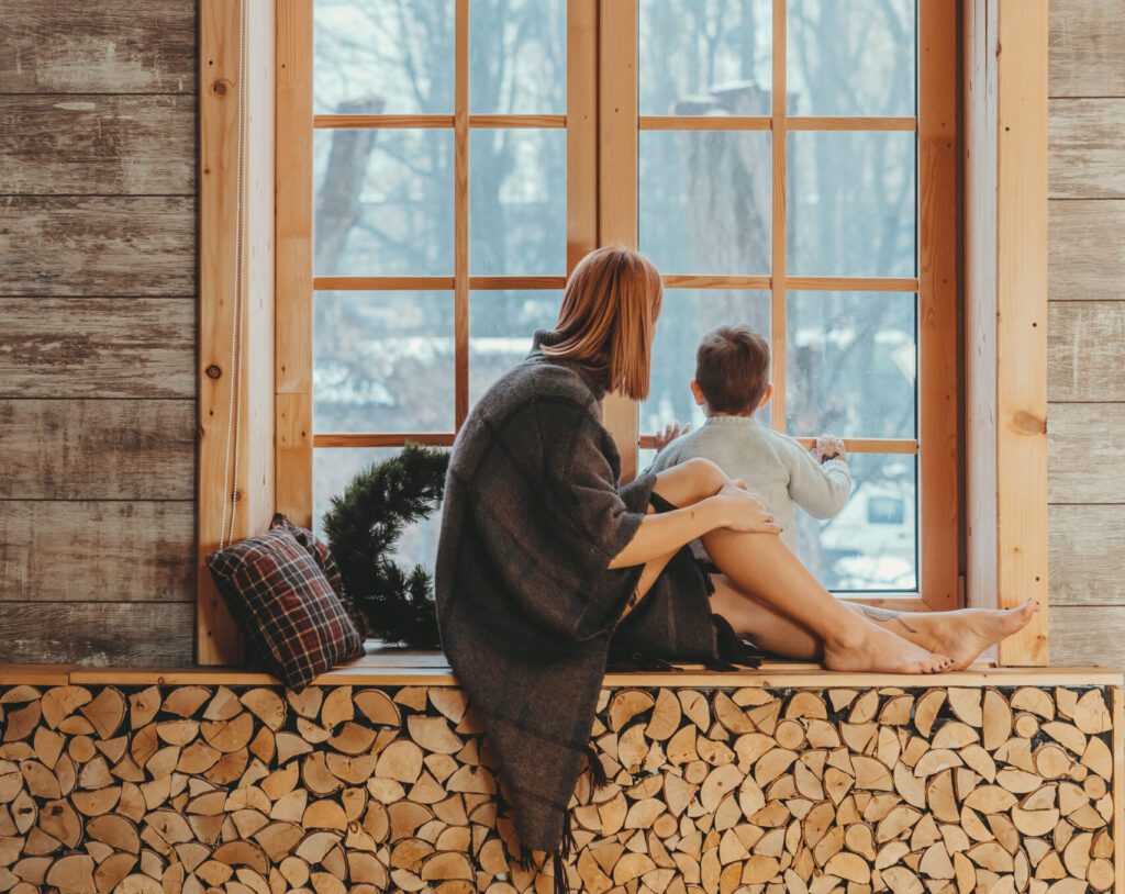 Young mom and beautiful baby sitting on the windowsill and playing.